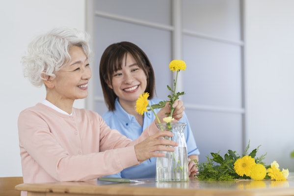 花を生けるレクをする高齢者女性と介護士