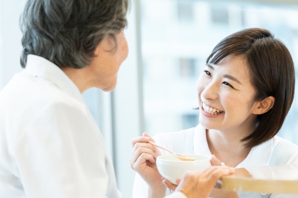 笑顔で器とスプーンを持つ女性と高齢者