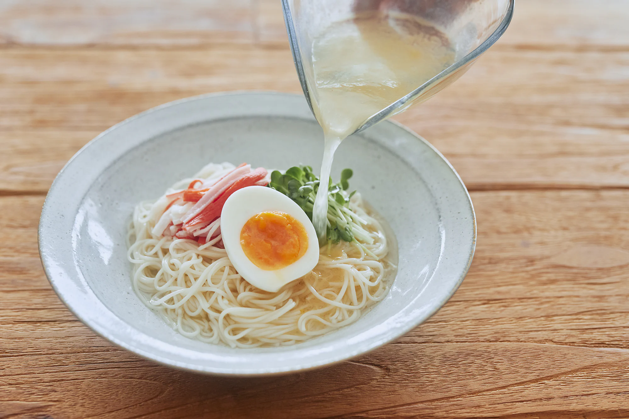 冷たいスープを麺にかける様子