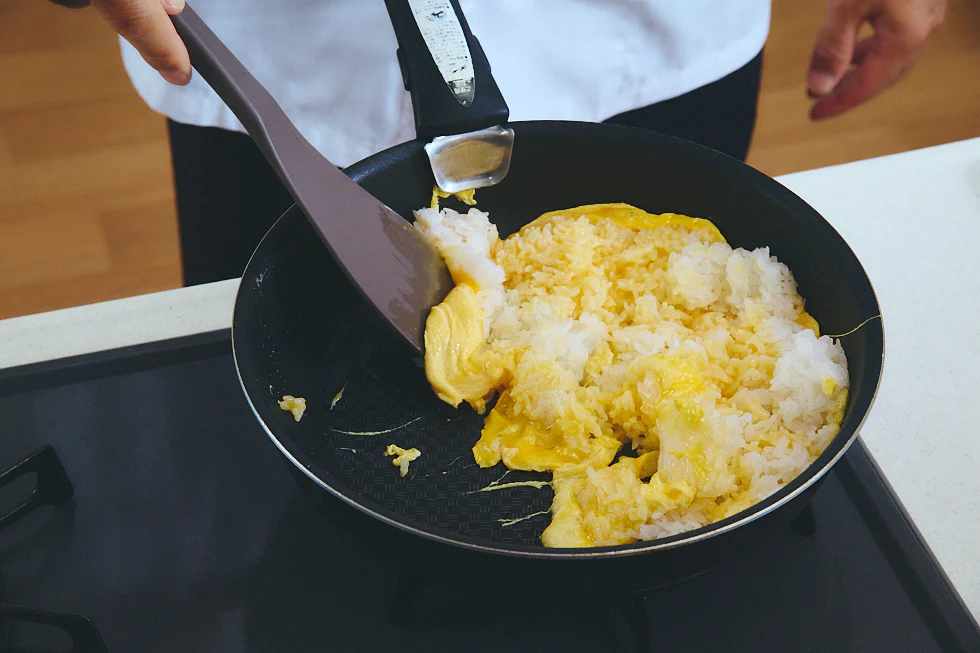 ご飯と卵が合わせった状態でフライパンで炒めている様子
