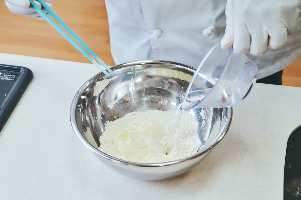 強力粉 、薄力粉、塩が入ったボウルにお湯を入れている