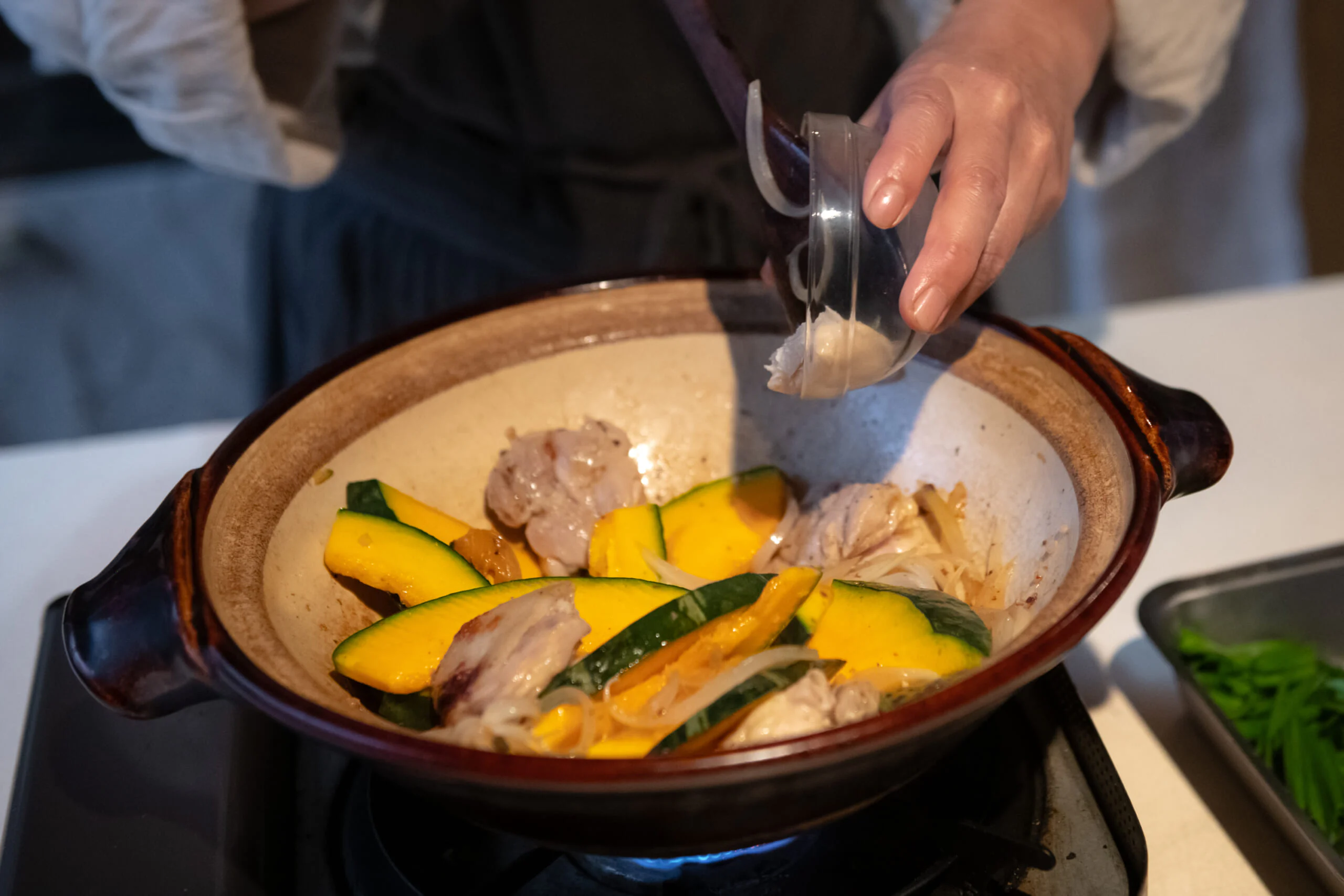 皮目に焼き色がついたら裏返し、玉ねぎ、かぼちゃ、にんにくを加えて炒めます。玉ねぎがしんなりしたら、酒粕を加えて火を入れるように軽く炒め、酒と水を加えてふたをします。沸騰したら弱火にして15〜20分ほど煮込みます。