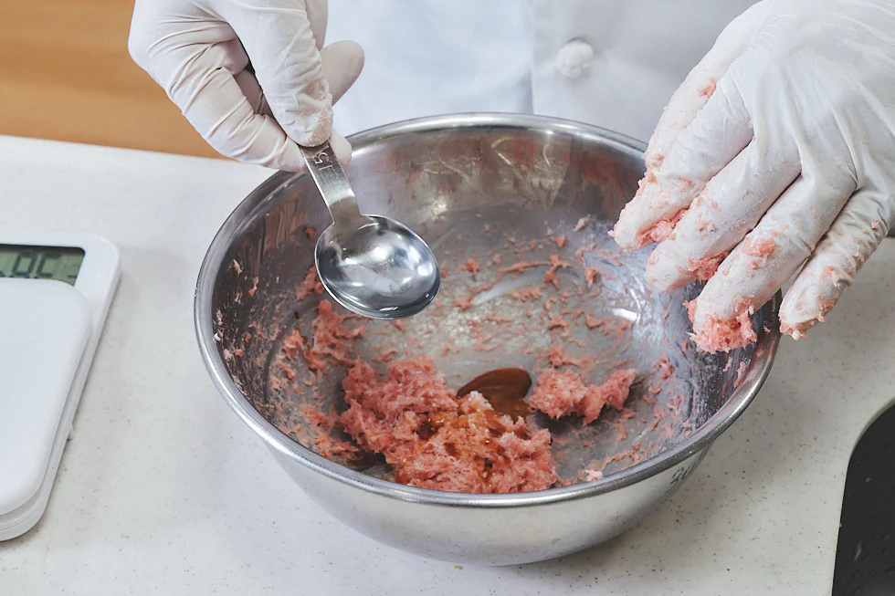 ひき肉の入ったボウルに調味料を入れる様子