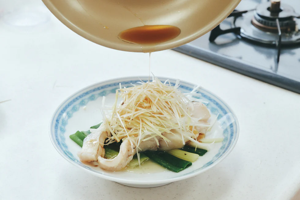 ごま油は、トロっとした状態からサラサラになるまで加熱したら、熱いうちにたらの皮、長ねぎ、しょうがにかかるように回しかけます