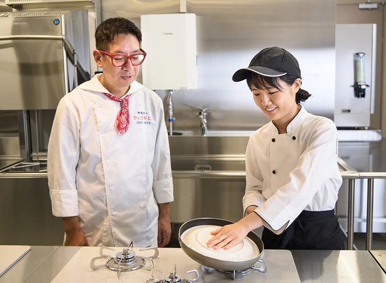 焼き上がったフライパンの上に白い大皿をかぶせ、ひっくり返す準備をする竹内さん
