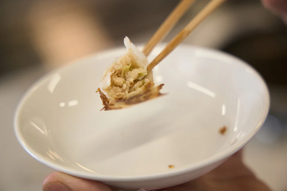 箸でひとつ持ち上げられた「ギョーザ」の断面