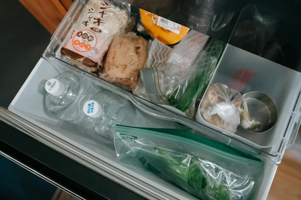 浅い引き出しには、細々した食材を。きのこなど傷みやすい食材、使いかけの食材もここに収納。にんにくはバラバラになりやすいので、丸缶にまとめる。下段はねぎやごぼうといった長い野菜、白菜などの大きな野菜を収納。葉ものは鮮度を保つため保存袋に入れる