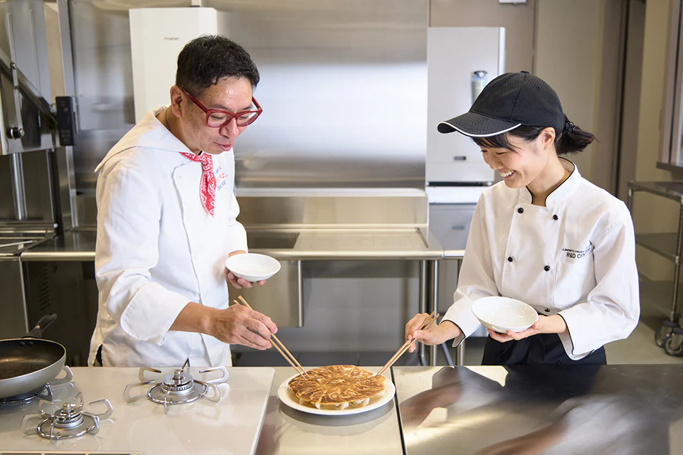 完成した「AJINOMOTO BRANDギョーザ」の皿を囲み、楽しそうに箸を伸ばすクック井上。さんと竹内さん