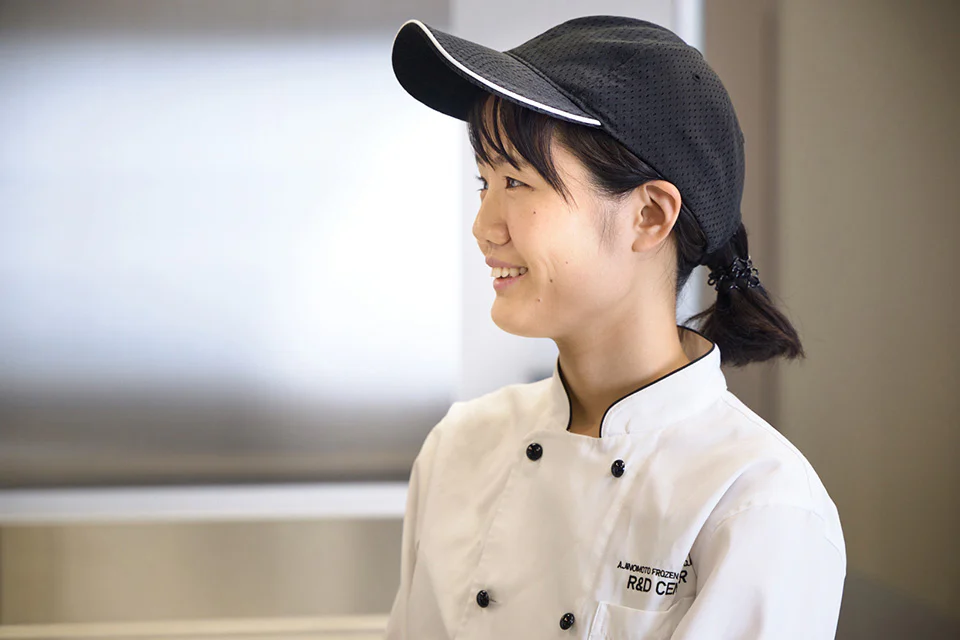 黒いキャップと白いコックコートを着て微笑む「AJINOMOTO BRANDギョーザ」開発担当の竹内さん