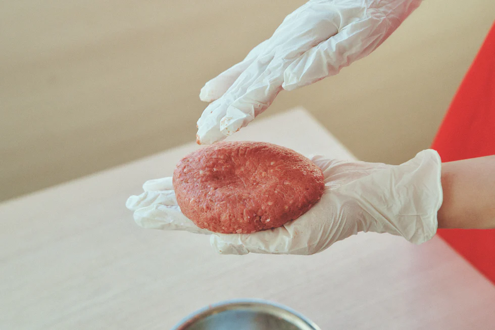 こねたひき肉を丸めて、表面にひび割れがないよう厚さ1.5cmの小判型に整え、真ん中をくぼませる