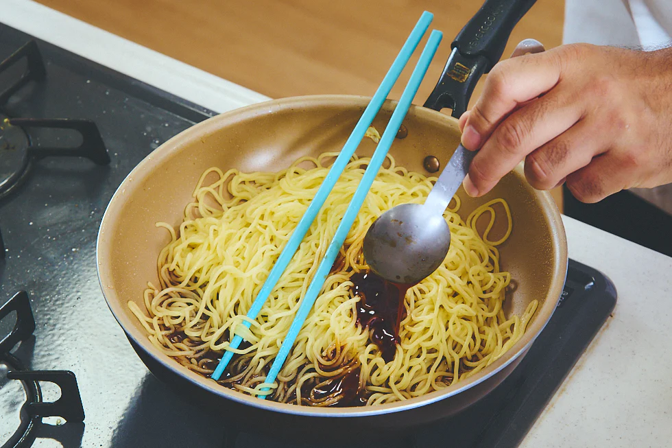 麺の入ったフライパンにソースを入れる様子