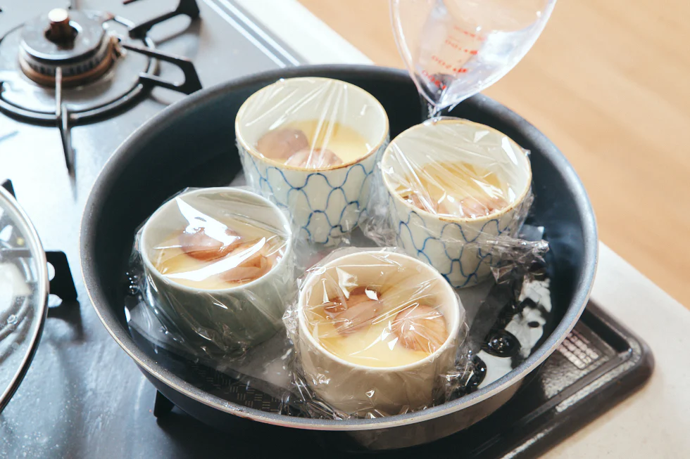 フライパンに器を並べたら、器の半分の高さまで水を注ぎます