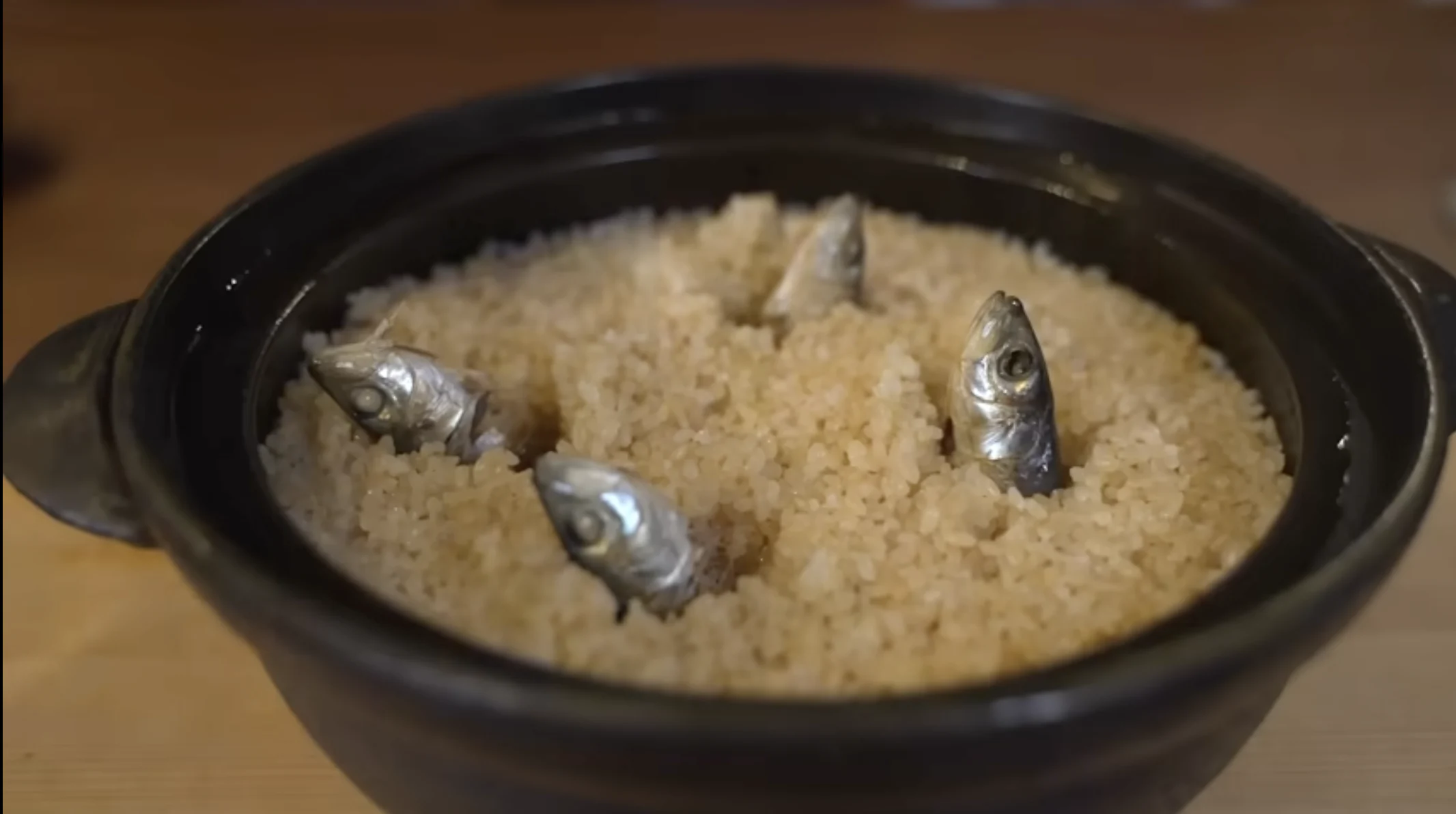 イワシの頭部だけがのぞく土鍋に入ったイワシ飯の画像