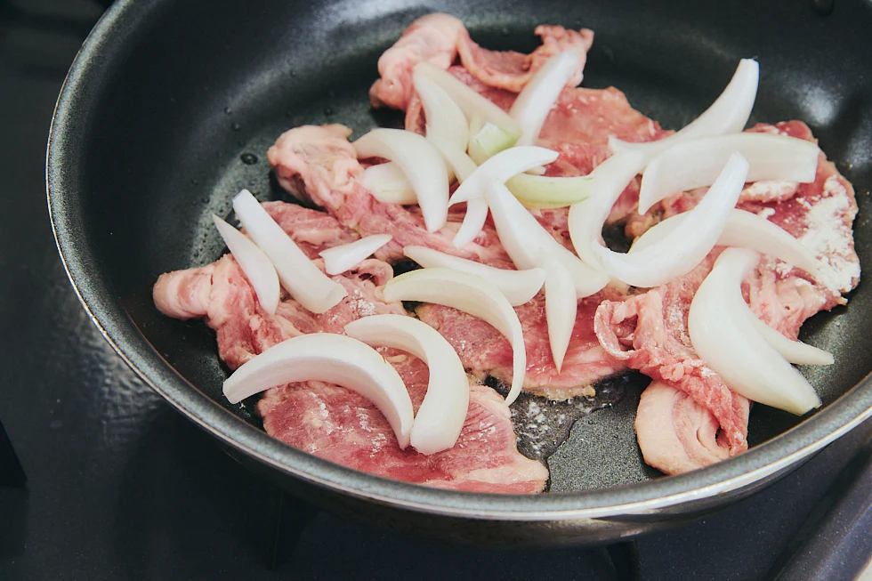 フライパンに肉と玉ねぎが入っている様子