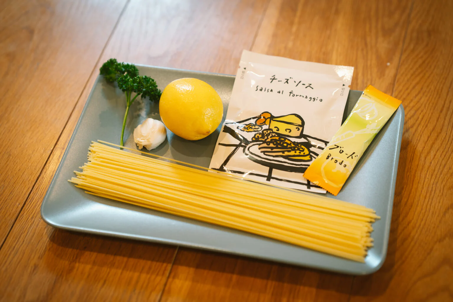 「レモンのパスタ」の基本の材料。「ミオブロード」〈チーズ〉に入っているブロード1袋、チーズソース1袋、パスタ100g、にんにく1かけ、パセリ、レモン、たったこれだけ!1袋で1人前のパスタが作れる。