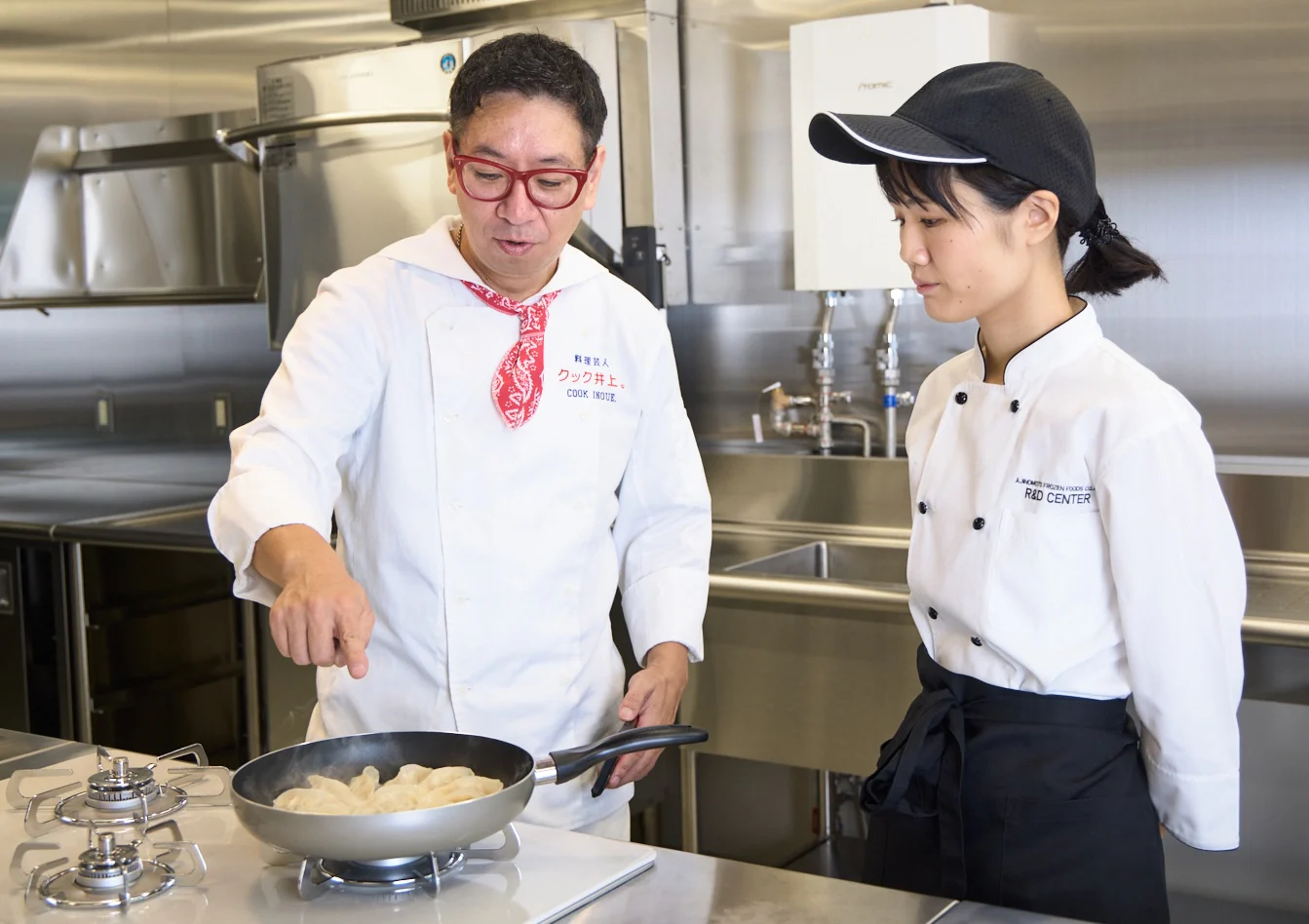 フライパンを真剣に覗き込むクック井上。さんと、その横で見守る竹内さん