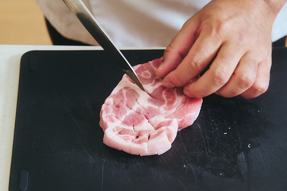 豚肉に切れ込みを入れている様子