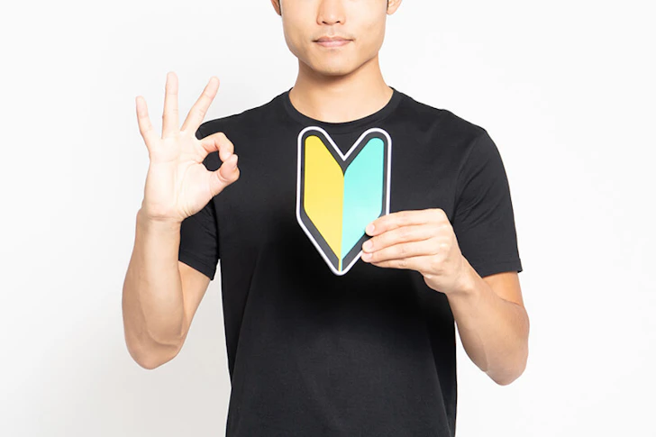 初心者マークを持った男性が手でOKサインを出している