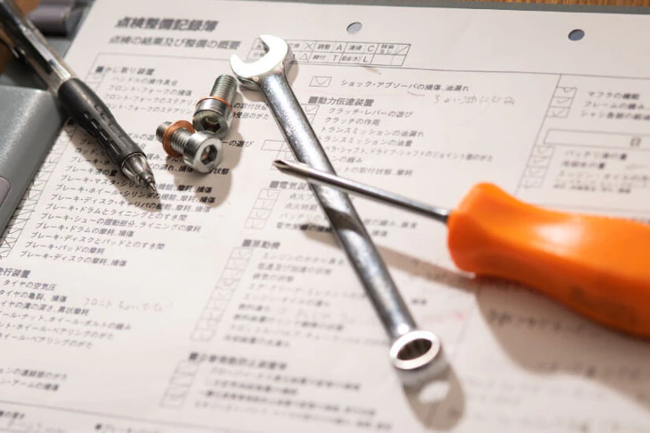 資料の上にボールペンやドライバーが置かれている