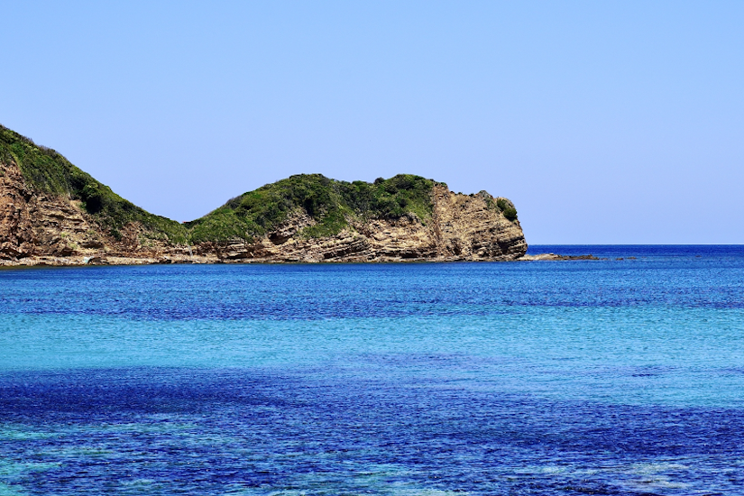 背景に青空が広がり、海に浮かぶ島が見える。