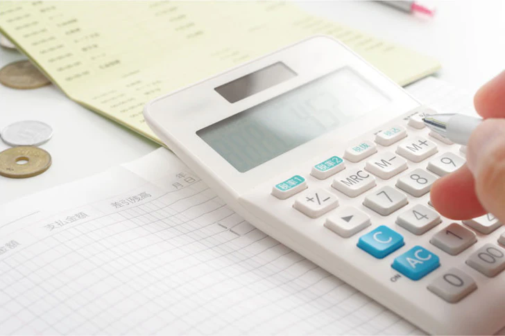 電卓でお金の計算をしている手元