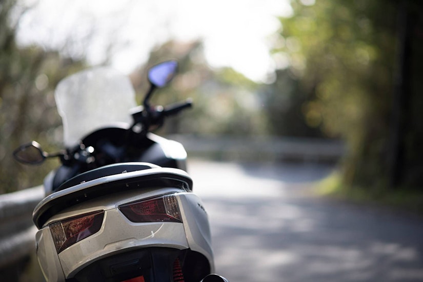 日差しが差し込む道に停められたバイクの後ろ姿