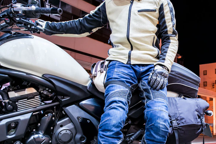 バイクに腰をかける手袋をした男性