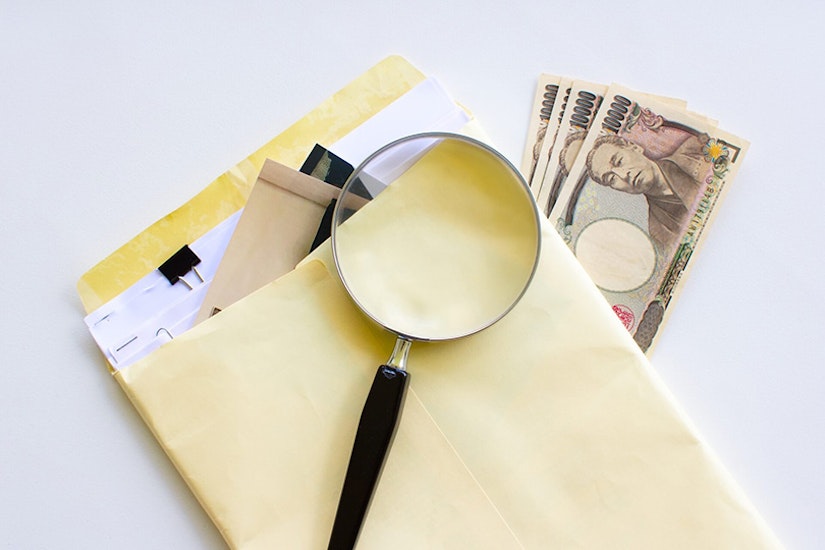 封筒、虫眼鏡、現金が置かれている