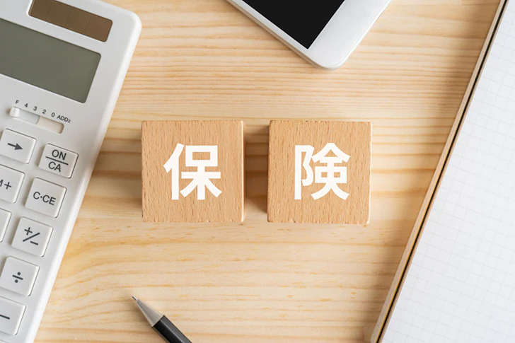 保険と書かれたブロック、電卓、スマホ