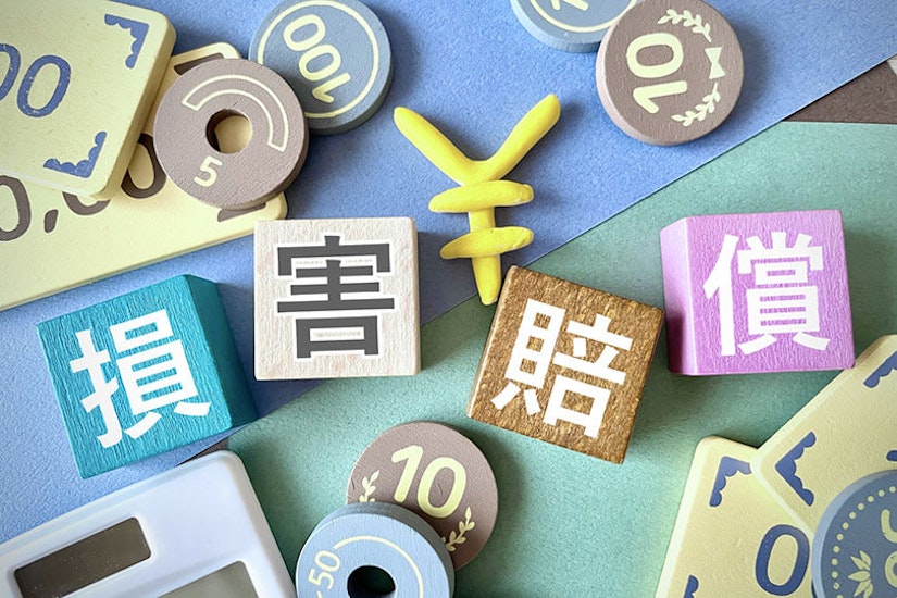 損害賠償と書かれた置き物の周りにコインや電卓も置いてある。