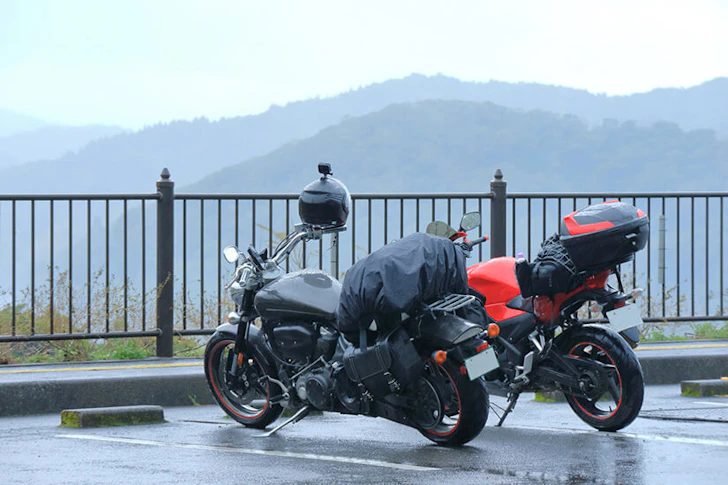 駐車場に止められたバイク2台の奥に山が広がっている