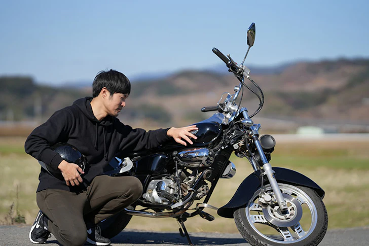 バイクの車体を屈んで確認している男性