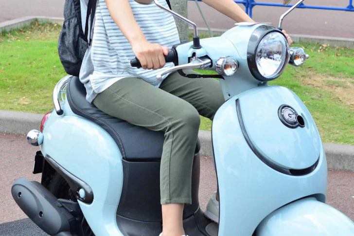 水色の原付に乗車している女性