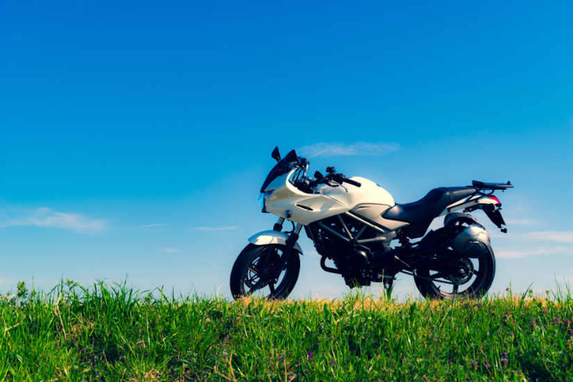 青空を背景にして、芝生の上に白と黒のバイクが駐車されている