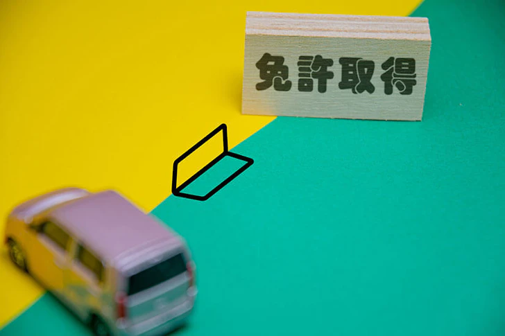 免許取得と書かれたオブジェに初心者マーク、車のミニチュアが置かれている