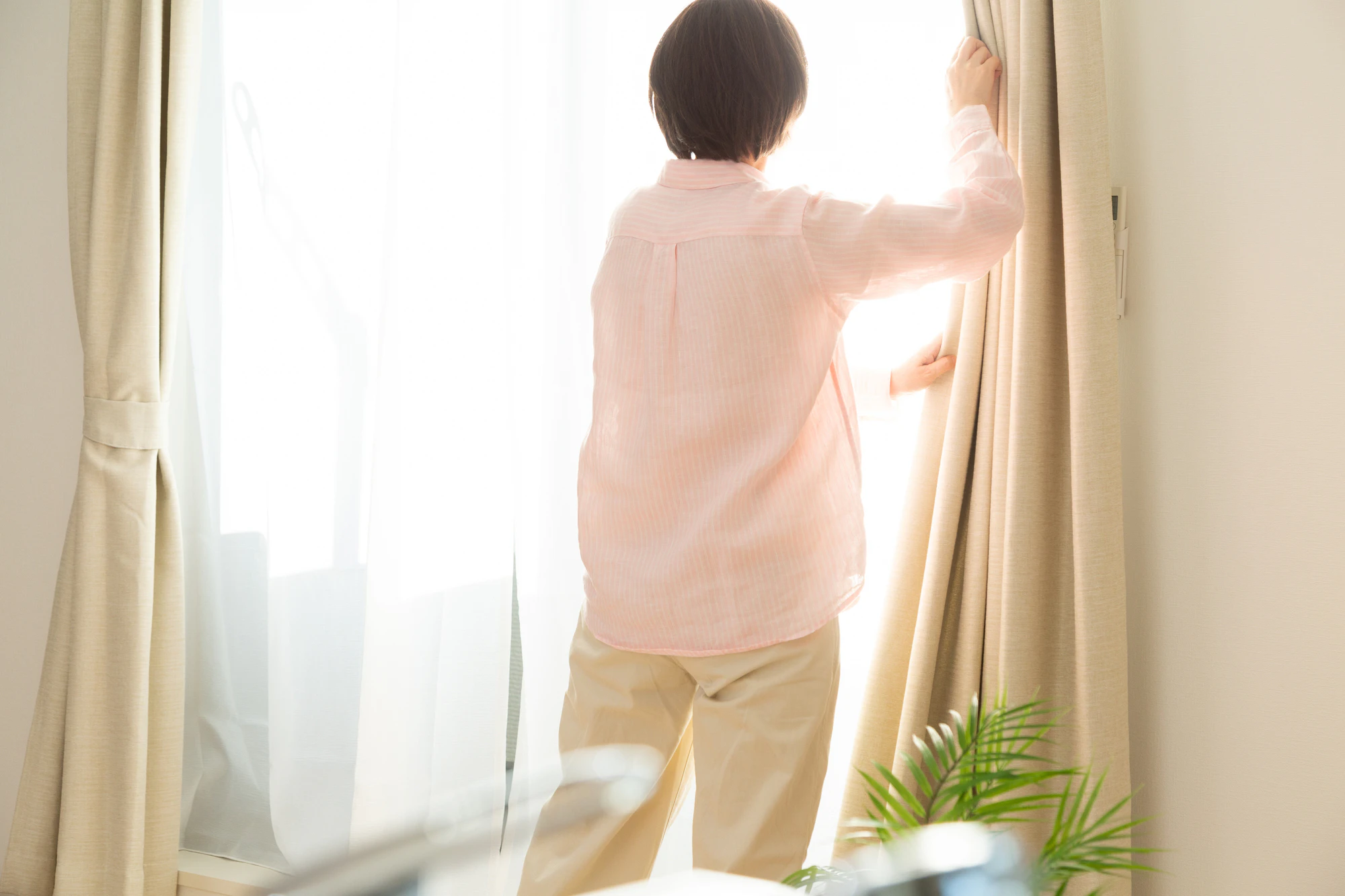カーテンを開けるミドル女性