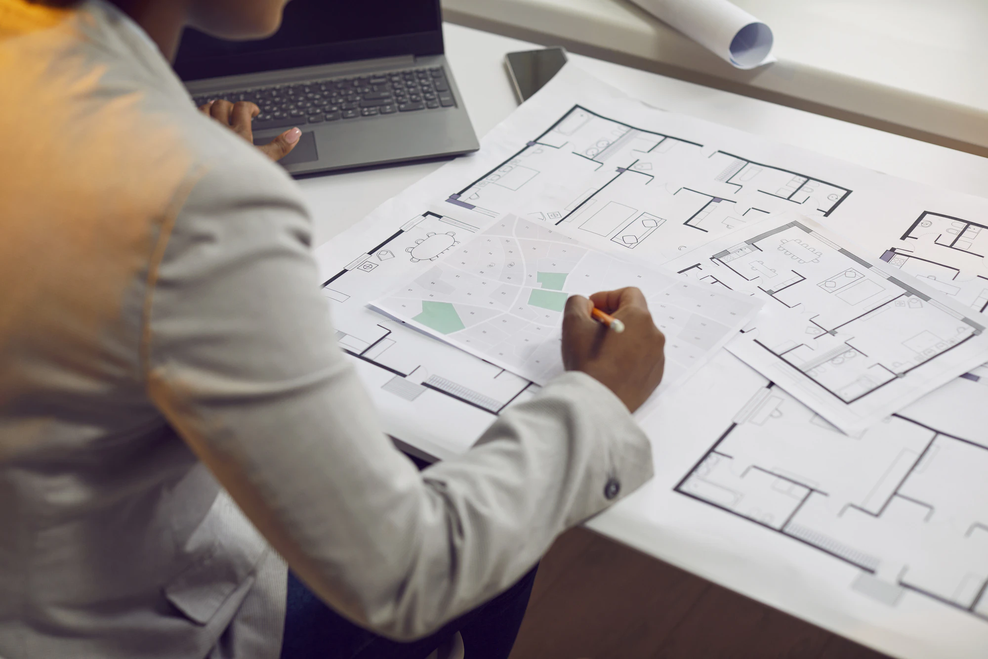 Woman architect working on blueprints and using urban plans and cadastral city maps