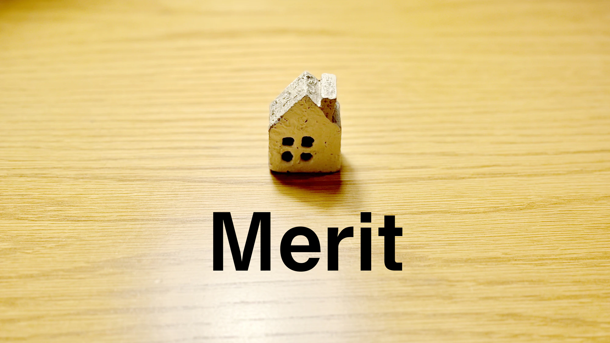 スポットライトの当たったテーブルにポツンと置いた家小物とMerit文字