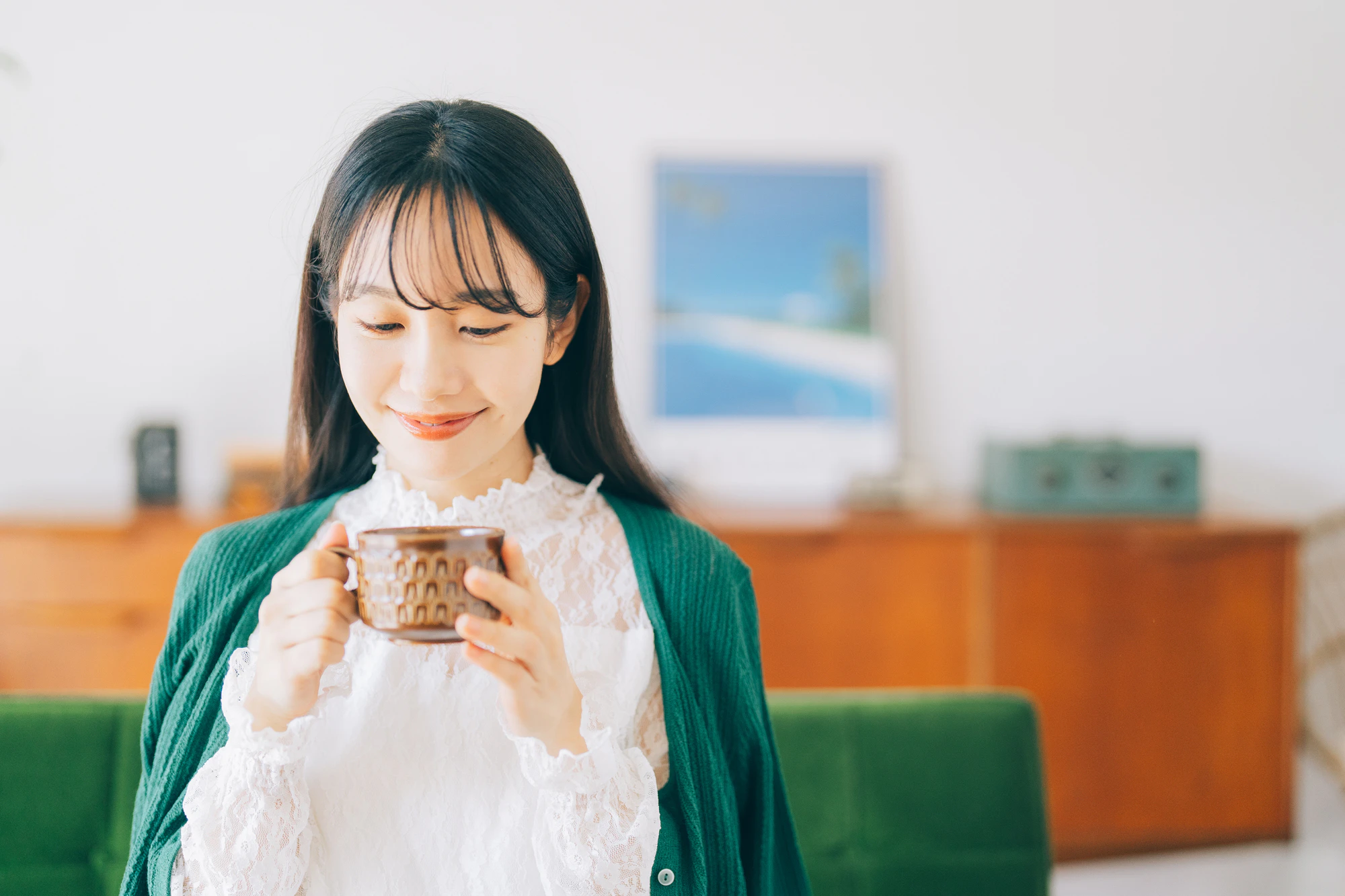 ソファに座ってコーヒーを飲む女性