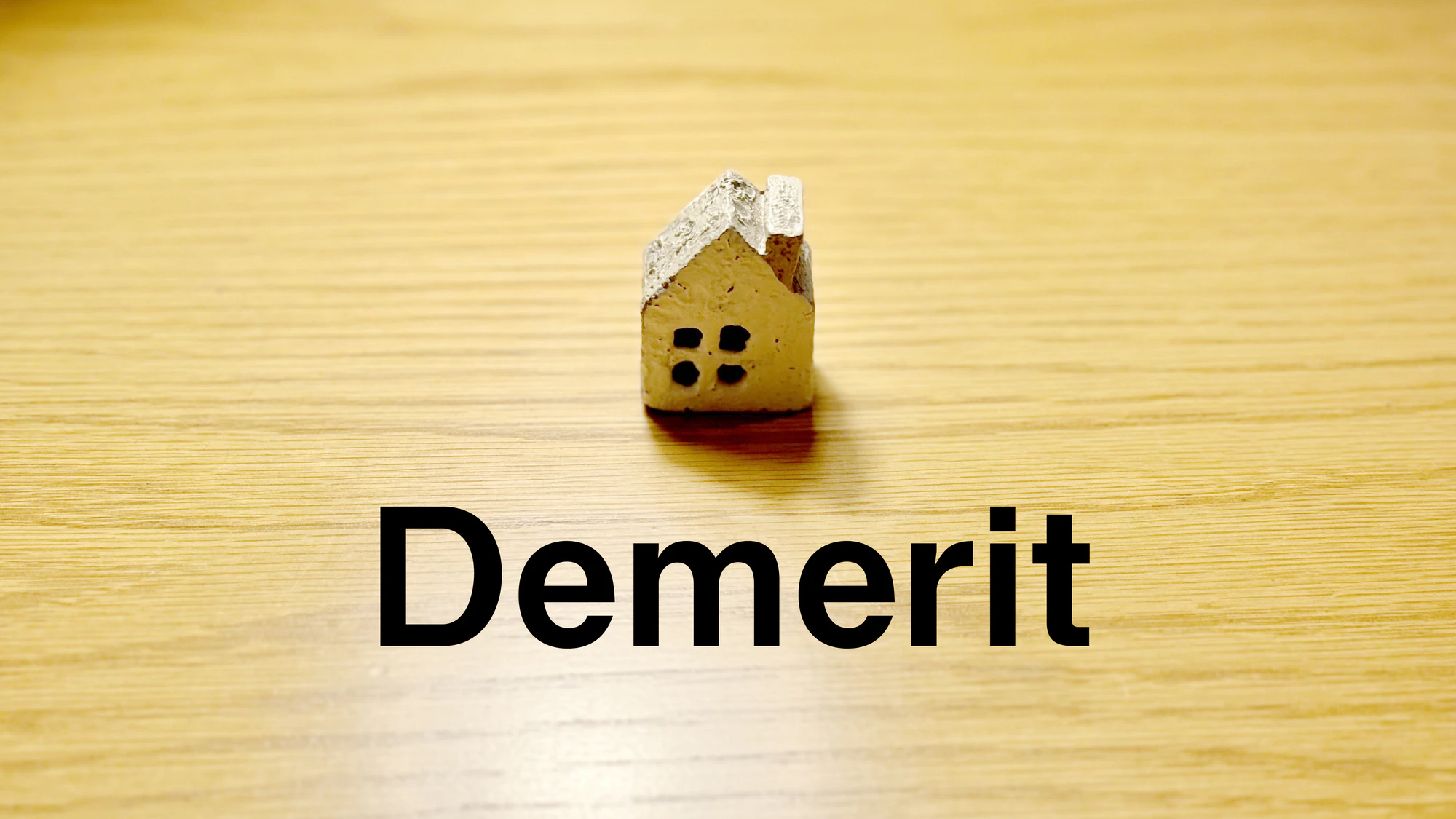スポットライトの当たったテーブルにポツンと置いた家小物とDemerit文字