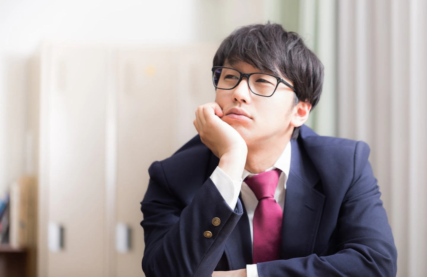 頬杖をついて考え込むスーツ姿の男性
