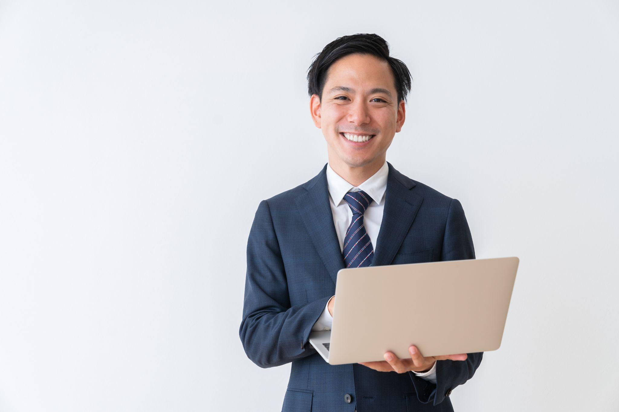 ノートパソコンを持って微笑んでいる男性