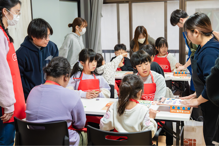 NPO法人キッズフリマのイベントで大人と子どもがワークショップに取り組む写真