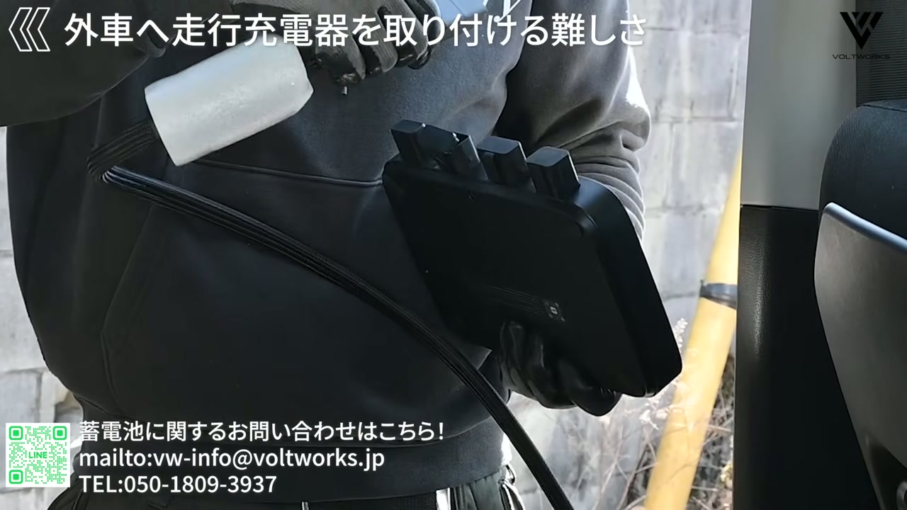 輸入車の車体下から走行充電器の配線を取り付けるスタッフ