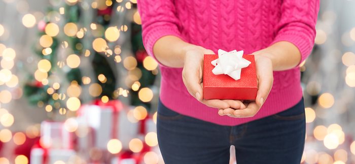 close up of woman in pink sweater holding gift box