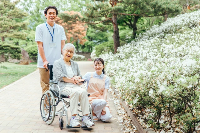 車椅子の高齢女性と二人のスタッフ
