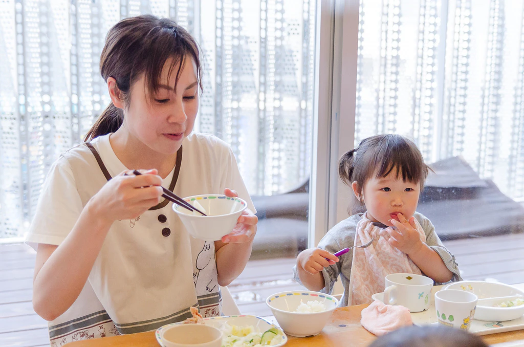 子どもと一緒に給食を食べる保育士さん