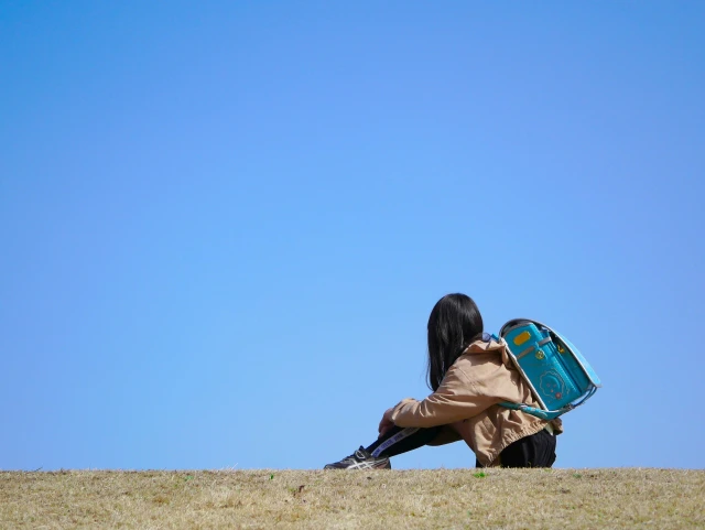 一人で川辺に座る小学生