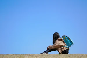 一人で川辺に座る小学生