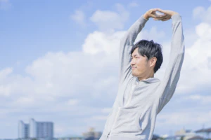 青空の下で伸び伸びとする男性